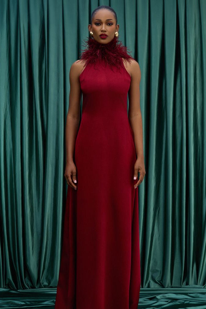 Woman in a red dress standing against a green curtain backdrop