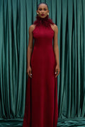 Woman in a red dress standing against a green curtain backdrop