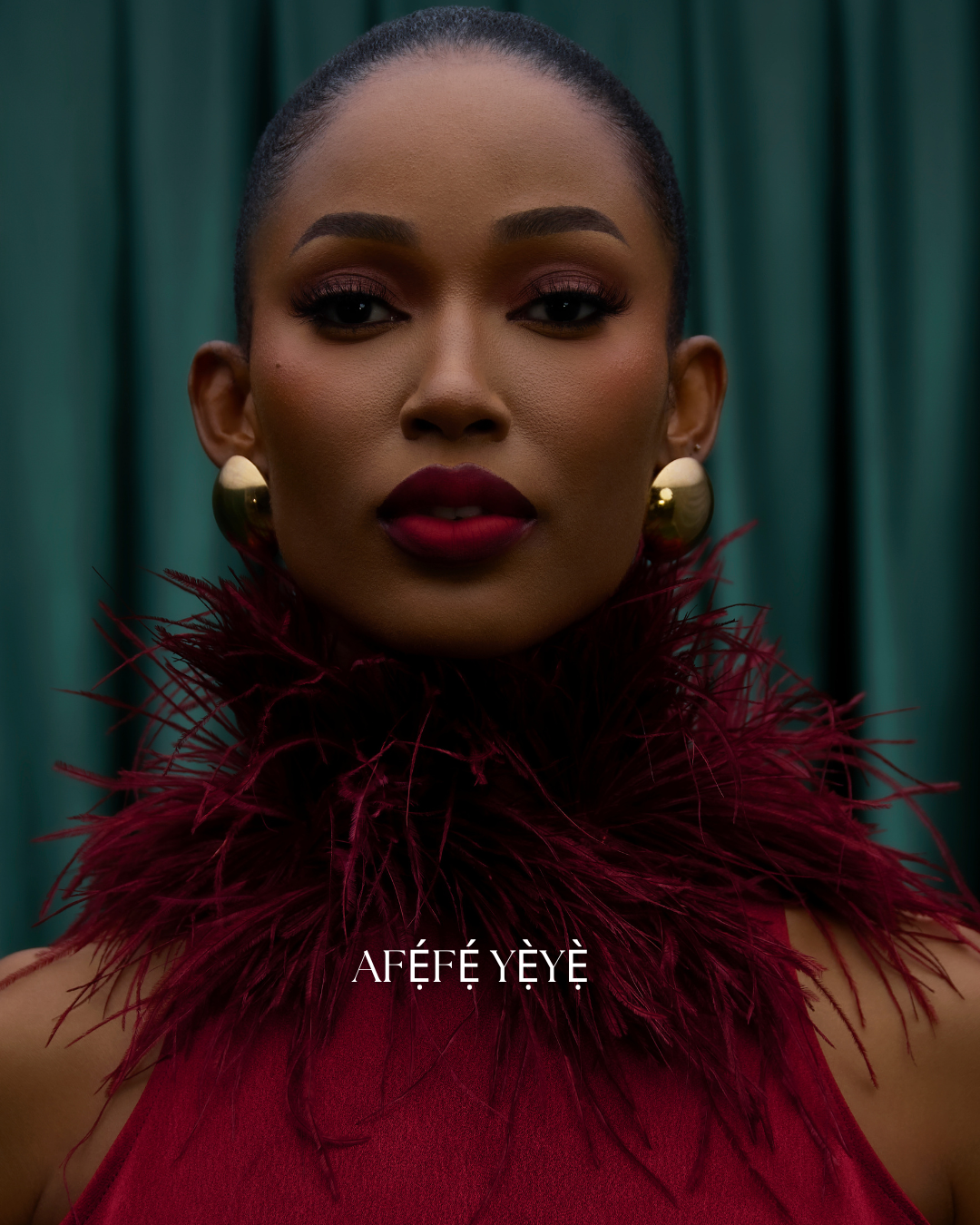 Woman wearing a red feathered garment with 'Aféfé Yèyé' branding against a green curtain background.